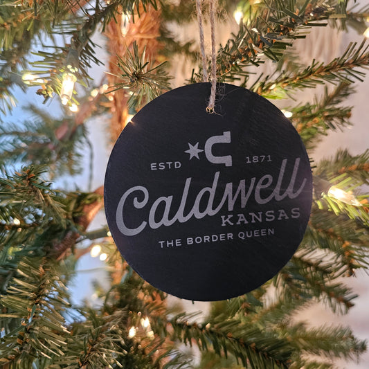 Engraved slate ornament featuring Caldwell’s Border Queen city logo with kraft packaging